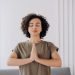 Young woman with curly hair meditates indoors, embracing tranquility and mindfulness.