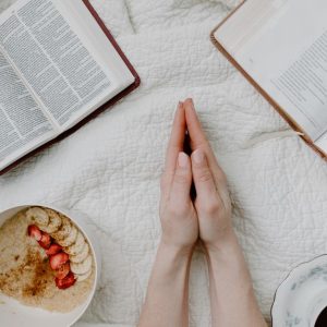 A serene morning scene with a person praying, an open Bible, oatmeal, and coffee.