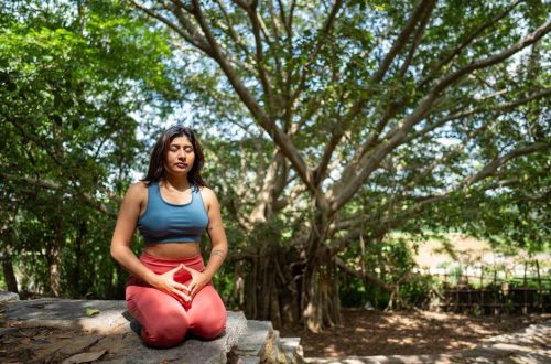A woman practicing meditation under a banyan tree in nature, promoting tranquility and mindfulness.