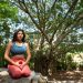 A woman practicing meditation under a banyan tree in nature, promoting tranquility and mindfulness.