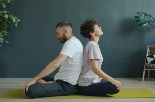Casal meditando de costas um para o outro em um espaço de meditação acolhedor e tranquilo