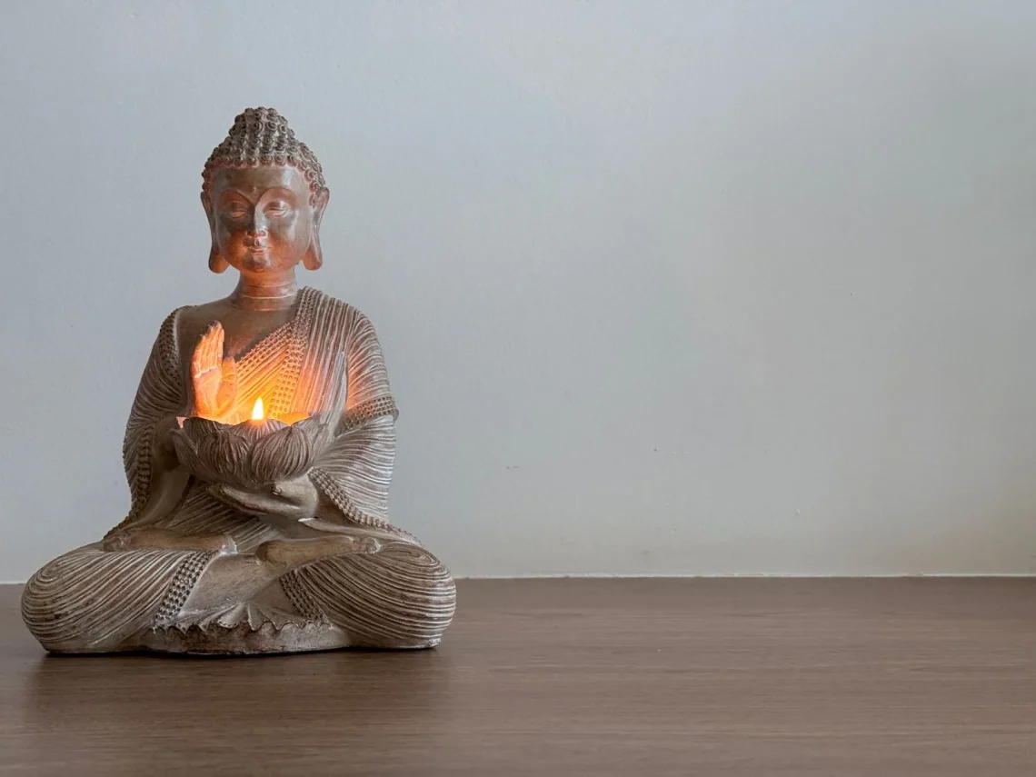 Estátua de Buda em um ambiente sereno com velas acesas, perfeito para criar um espaço de meditação