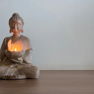 Estátua de Buda em um ambiente sereno com velas acesas, perfeito para criar um espaço de meditação