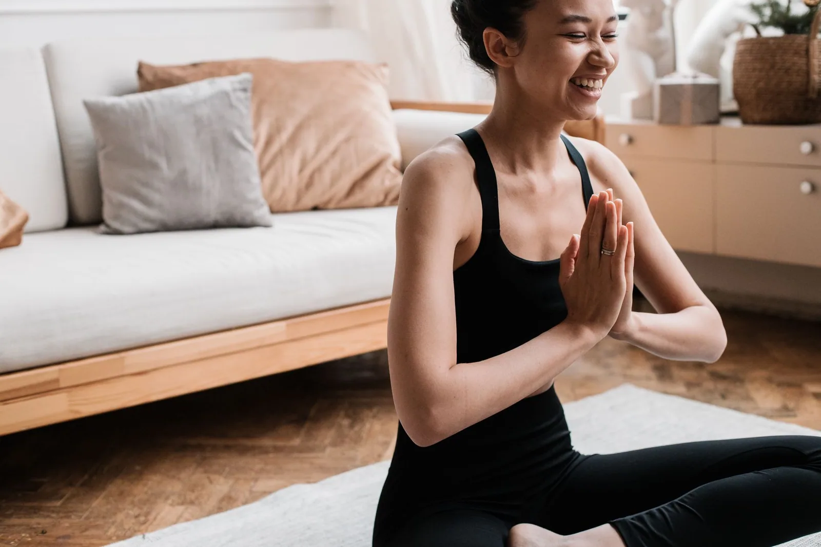 Mulher alegre meditando em um ambiente interno tranquilo, destacando a promoção do bem-estar mental e relaxamento