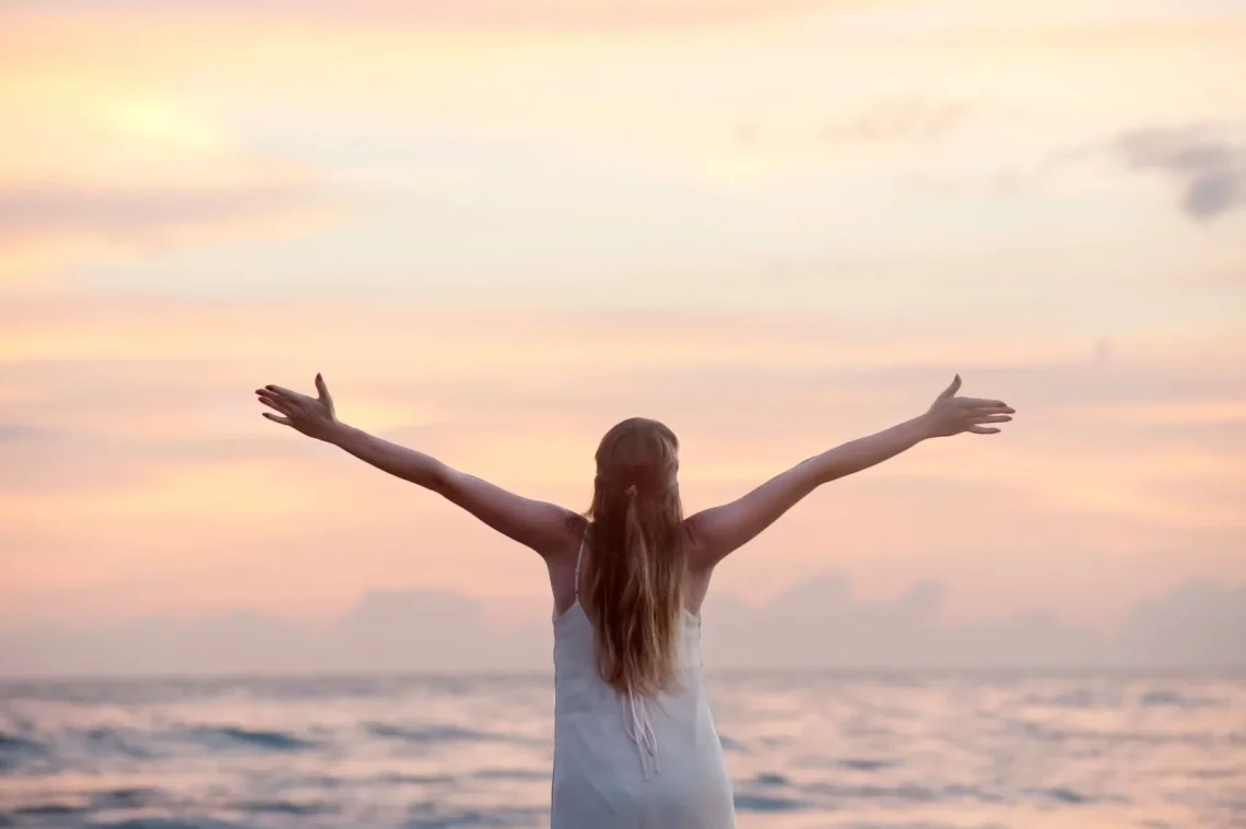 Mulher desfrutando de um pôr do sol sereno na praia de Unawatuna, simbolizando a gratidão na meditação