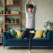 Mulher praticando yoga em sala de estar moderna com plantas e decoração aconchegante, ideal para um espaço de meditação