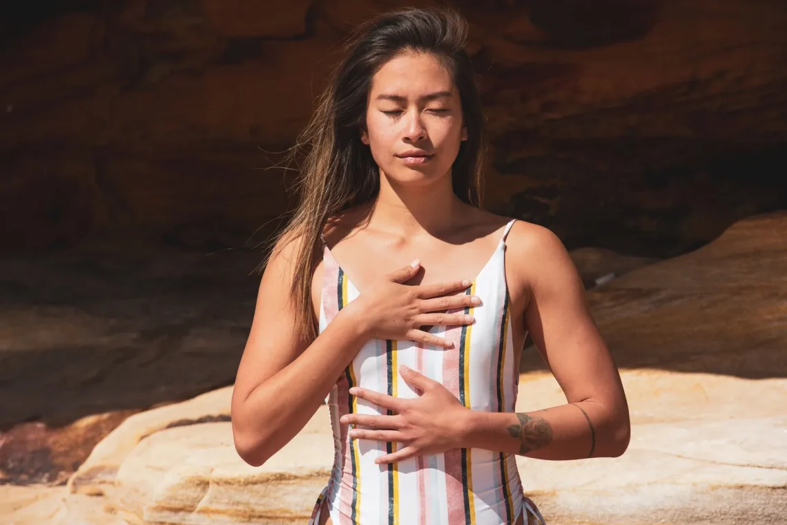 Mulher relaxa ao ar livre com respiração profunda, em estado meditativo, refletindo sobre gratidão na meditação
