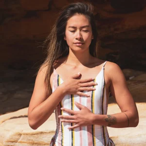 Mulher relaxa ao ar livre com respiração profunda, em estado meditativo, refletindo sobre gratidão na meditação