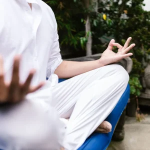 Pessoa vestindo branco meditando ao ar livre em um ambiente sereno, simbolizando a gratidão na meditação