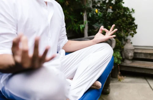 Pessoa vestindo branco meditando ao ar livre em um ambiente sereno, simbolizando a gratidão na meditação